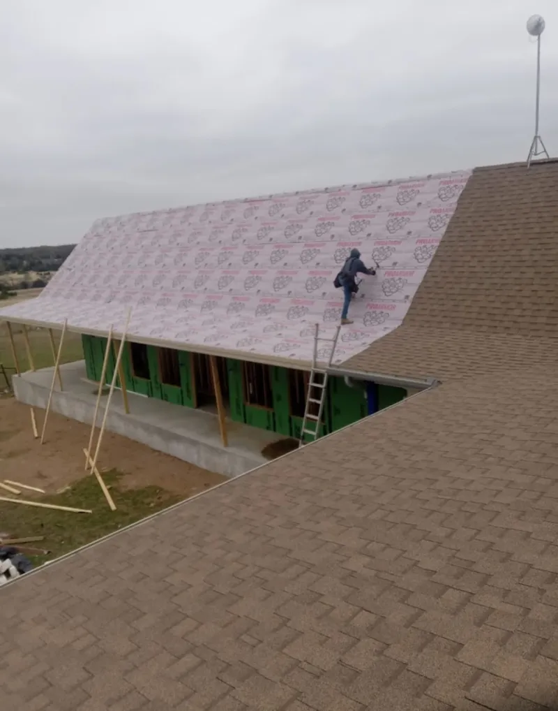 Worker preparing underlayment for a metal roof installation in Wakefield